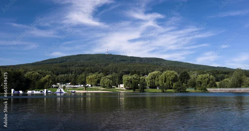 Timelapse of a small lake against a green hill, blue sky and white clouds, a beautiful sunny day Timelapse of a small lake against a green hill, blue sky and white clouds, a beautiful sunny day