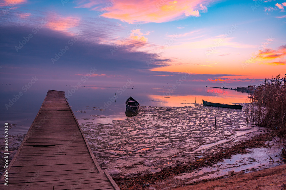 frozen boat in winter on the lake at sunrise