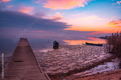 Obraz na płótnie frozen boat in winter on the lake at sunrise w salonie