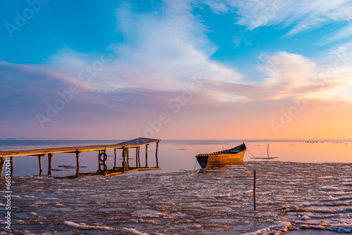 Obraz na płótnie frozen boat in winter on the lake at sunrise w salonie