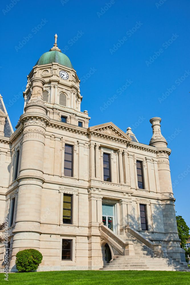 Green lawn and blue sky day with partial view of Whitley County Courthouse entrance with steps