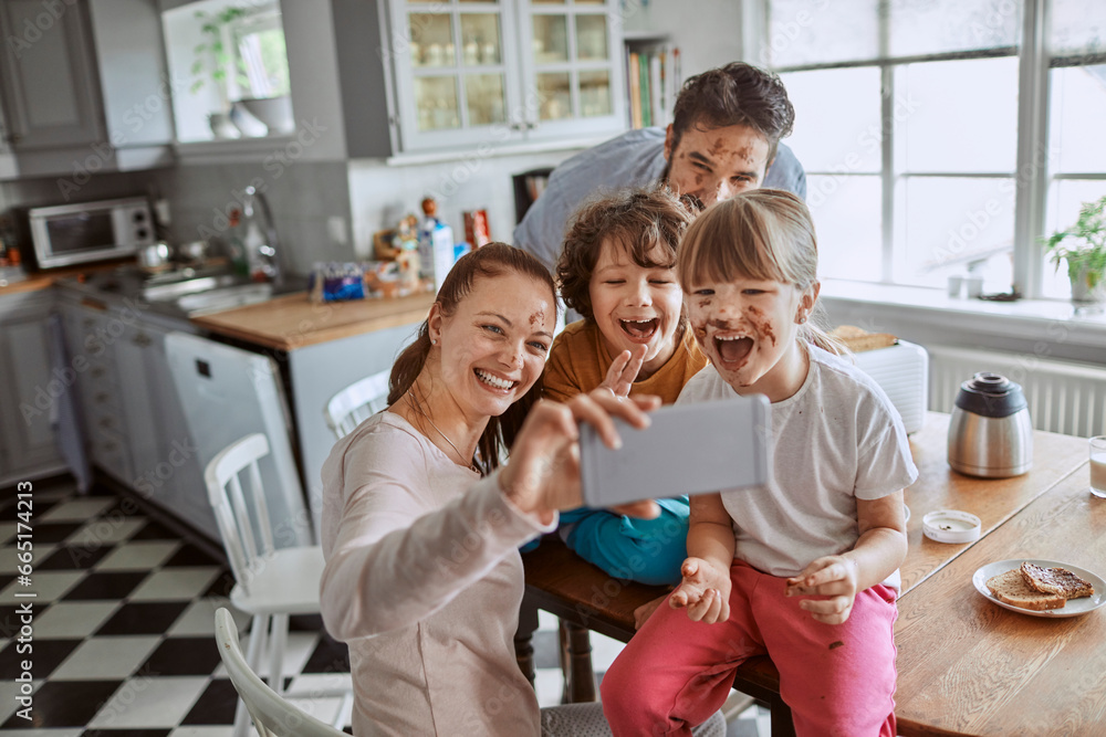 Happy young family taking a selfie in the kitchen after a messy breakfast Happy young family taking a selfie in the kitchen after a messy breakfast