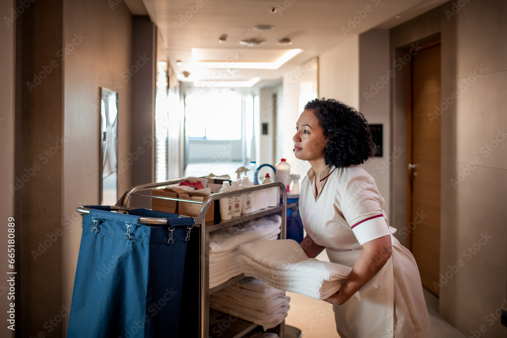 Hotel maid taking towels from a cleaning cart for the room Stock Photo