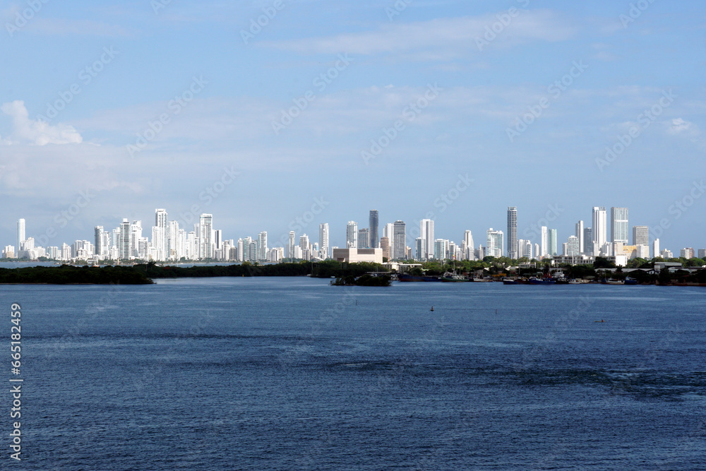 A distant silhouette of Cartegena, Colombia, with its tall modern buildings seen from the seaport on a sunny day.