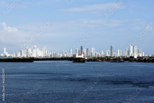 A distant silhouette of Cartegena, Colombia, with its tall modern buildings seen from the seaport on a sunny day. © Lucia