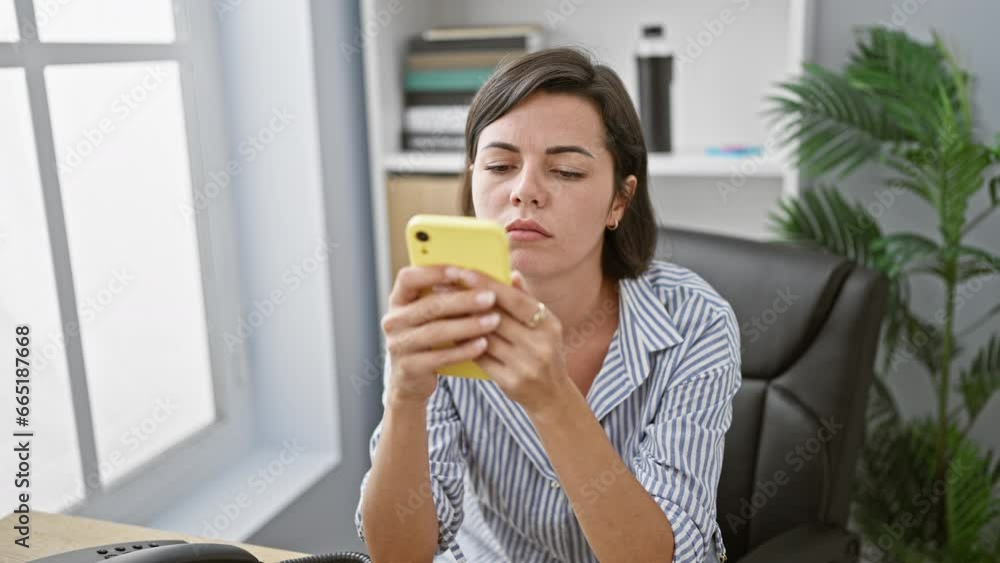 Upset young hispanic woman business worker holds smartphone in office, doubting her professional success, showcasing sadness amidst the indoor work hustle. Upset young hispanic woman business worker holds smartphone in office, doubting her professional success, showcasing sadness amidst the indoor work hustle.