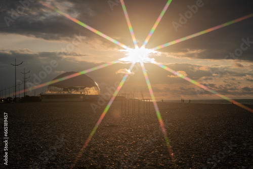 Batumi Georgia sunset sky, sand and stones, mountains, lens flare from the sun