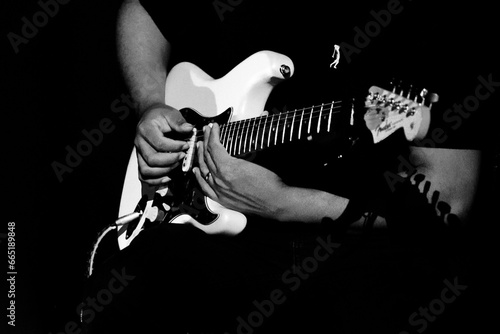 Guitarrista tocando sua guitarra branca em show em preto e branco.   photo