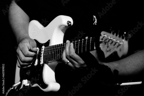 Guitarrista tocando sua guitarra branca em show em preto e branco. 
