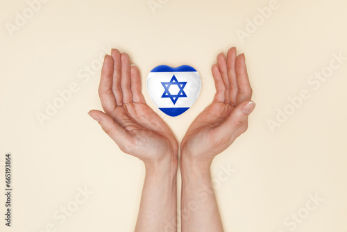 Heart with print of Israel flag in female hands. Flat lay.