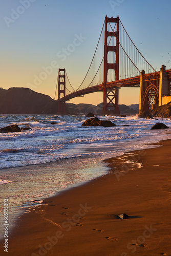 Footprints from bare feet coming out of water and waves with Golden Gate Bridge