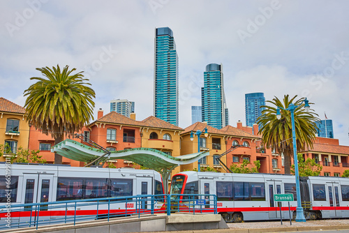 City transportation leaving Embarcadero bus stop with wavy overhang and skyscrapers behind houses photo