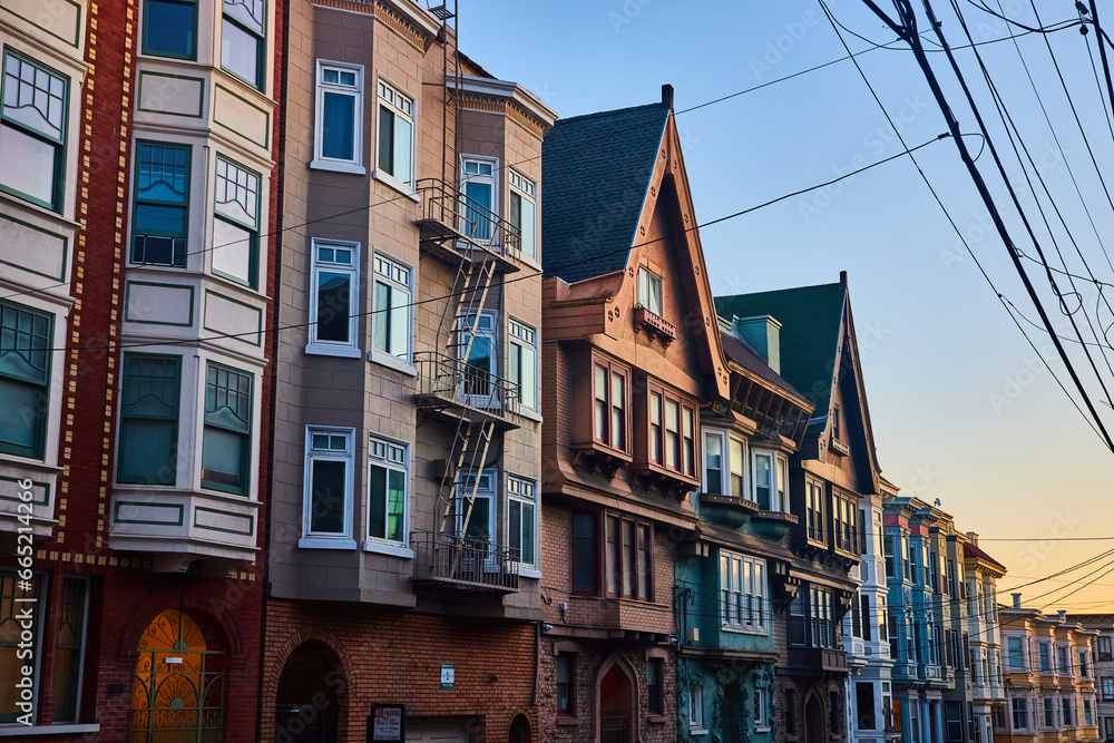 Fototapeta premium Yellow dusk lighting over row of California houses with peaked grooves on two in long line