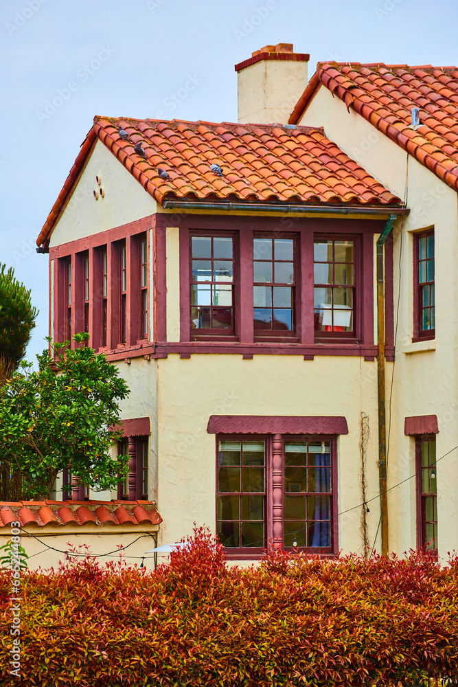 Fort Mason white building with maroon windows and orangish red tile roof with reddening bush