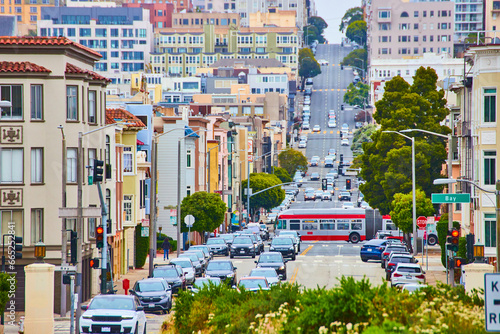 City bus cutting across traffic on busy road cutting through buildings on steep hill