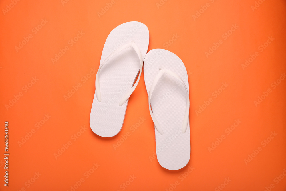 Stylish white flip flops on orange background, top view Stylish white flip flops on orange background, top view