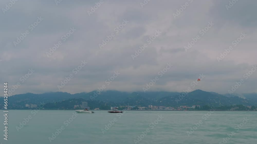 Timelapse: small motor boats, speedboats are moving fast, sailing on the Black Sea near Batumi harbor. Moving clouds over the mountains in the afternoon - time lapse Timelapse: small motor boats, speedboats are moving fast, sailing on the Black Sea near Batumi harbor. Moving clouds over the mountains in the afternoon - time lapse
