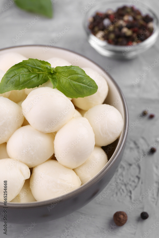 Tasty mozzarella balls and basil leaves in bowl on grey table, above view Tasty mozzarella balls and basil leaves in bowl on grey table, above view