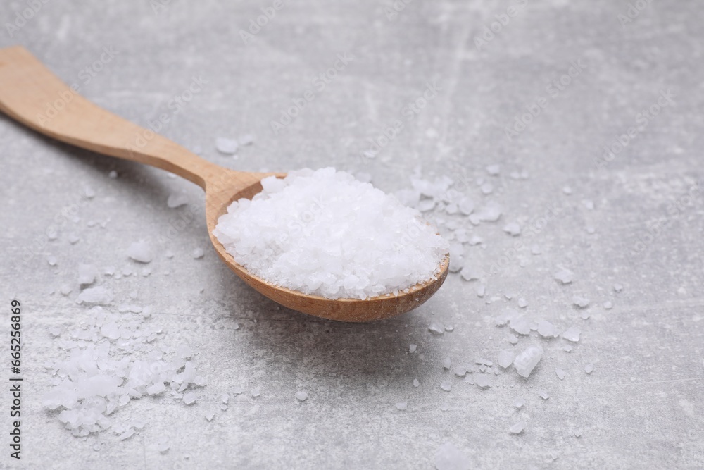 Spoon with sea salt on light grey table, closeup. Space for text Spoon with sea salt on light grey table, closeup. Space for text