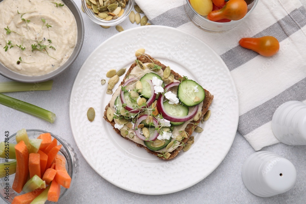 Tasty vegan sandwich with cucumber, onion, hummus and pumpkin seeds on light grey table, flat lay Tasty vegan sandwich with cucumber, onion, hummus and pumpkin seeds on light grey table, flat lay
