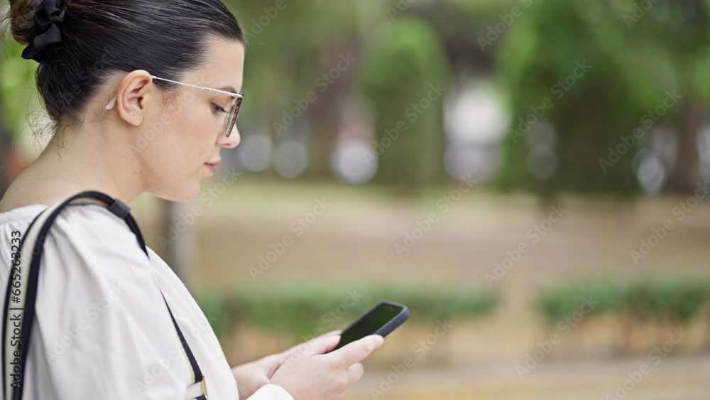 Young beautiful hispanic woman using smartphone walking at the park Young beautiful hispanic woman using smartphone walking at the park
