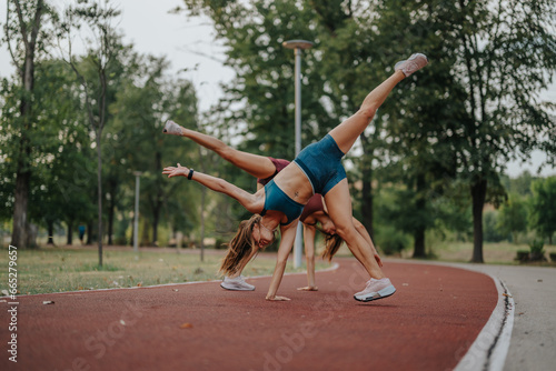 Fit, athletic sisters inspire with their flexibility and strength in an outdoor workout at dusk. Performing 360-degree cartwheels and flips, they exemplify a sporty, healthy lifestyle.