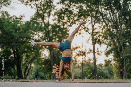 Fit girl demonstrating impressive flexibility and strength with 360-degree cartwheels in a green park. Motivating examples of an active, healthy lifestyle.