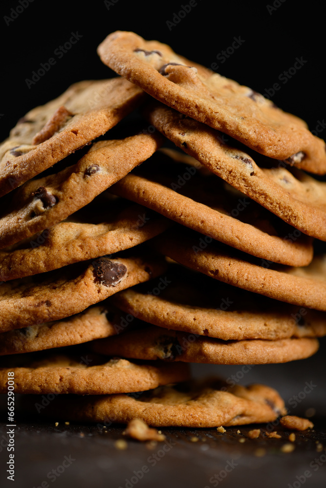 Multiple chocolate chip cookies stacked on black background Multiple chocolate chip cookies stacked on black background