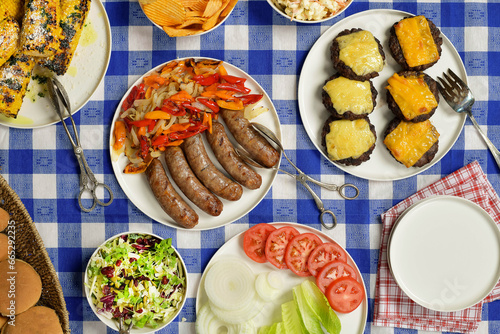 Summertime BBQ with bratwurst, burgers, cheese, corn, potato chips, salad, peppers, onions, tomatoes
