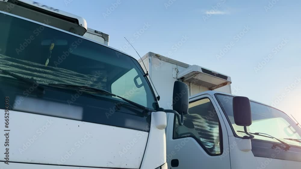 Medium refrigerated or reefer trucks wait at the truck stop for unload