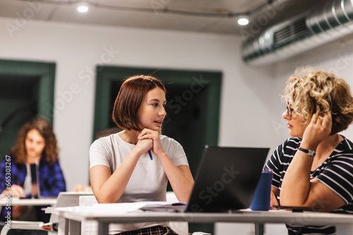 Junior and senior female coworkers brainstorm sharing ideas, discussing new business project while working together at modern office
