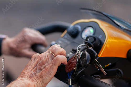 senior persons hands pushing buttons on electric mobility scooter vehicle photo