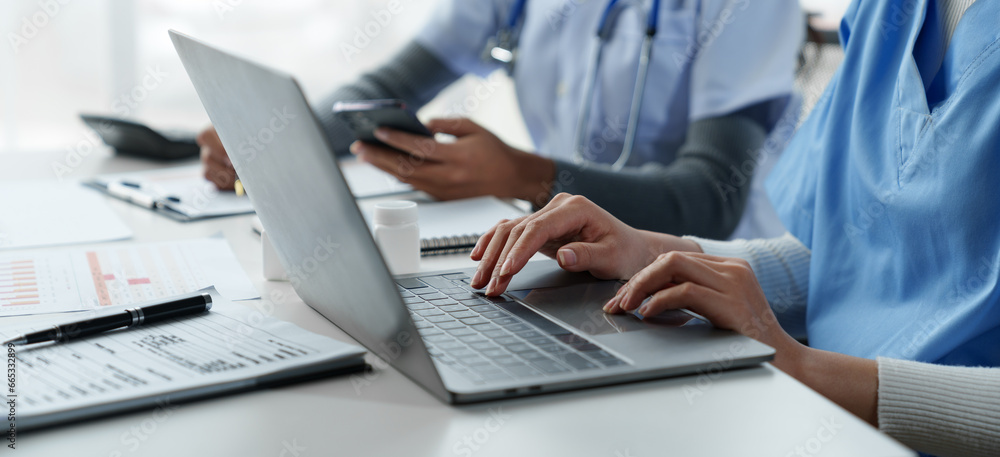 Confident female doctor, therapist sitting at table with medical stethoscope using laptop and mobile phone to write medical notes planning concept Study the treatment system Life insurance analysis. - obrazy, fototapety, plakaty 