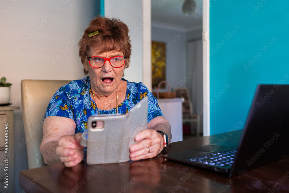 © Austockphoto - surprised older woman trying to use phone and laptop technology © Austockphoto - surprised older woman trying to use phone and laptop technology