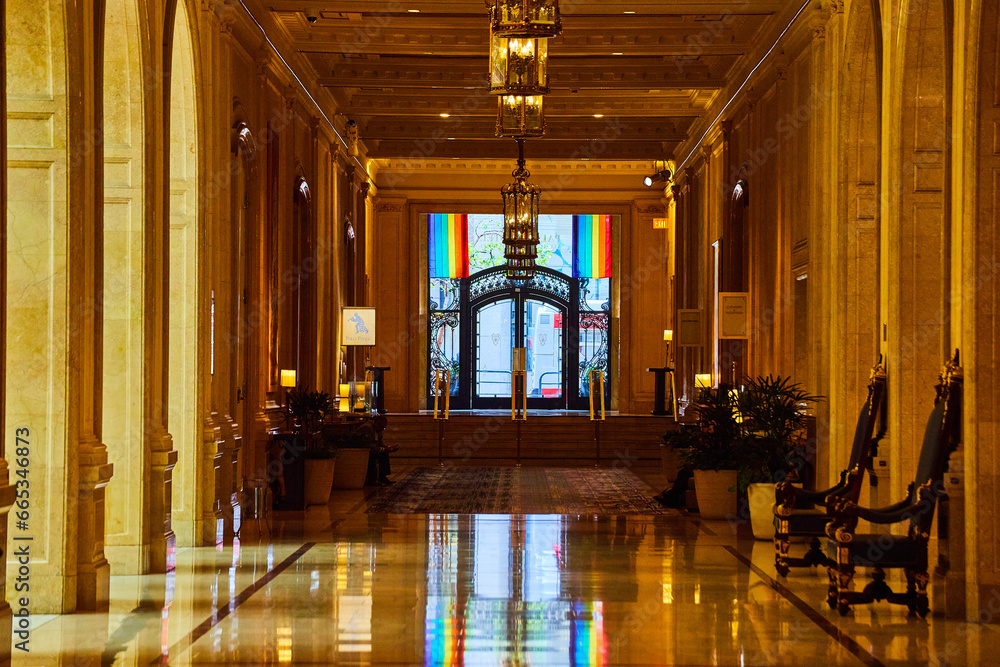 Fancy doorway framed by pride flags at end of golden reflective hallway