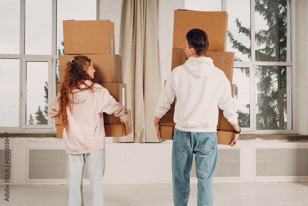 © primipil - Happy young family couple man and woman moving with cardboard boxes to new estate home apartment. Rear back view. © primipil - Happy young family couple man and woman moving with cardboard boxes to new estate home apartment. Rear back view.