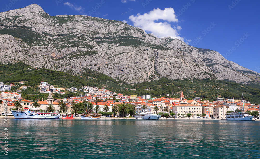Panorama and landscape of Makarska resort and its harbour with boats and blue sea water in Croatia
