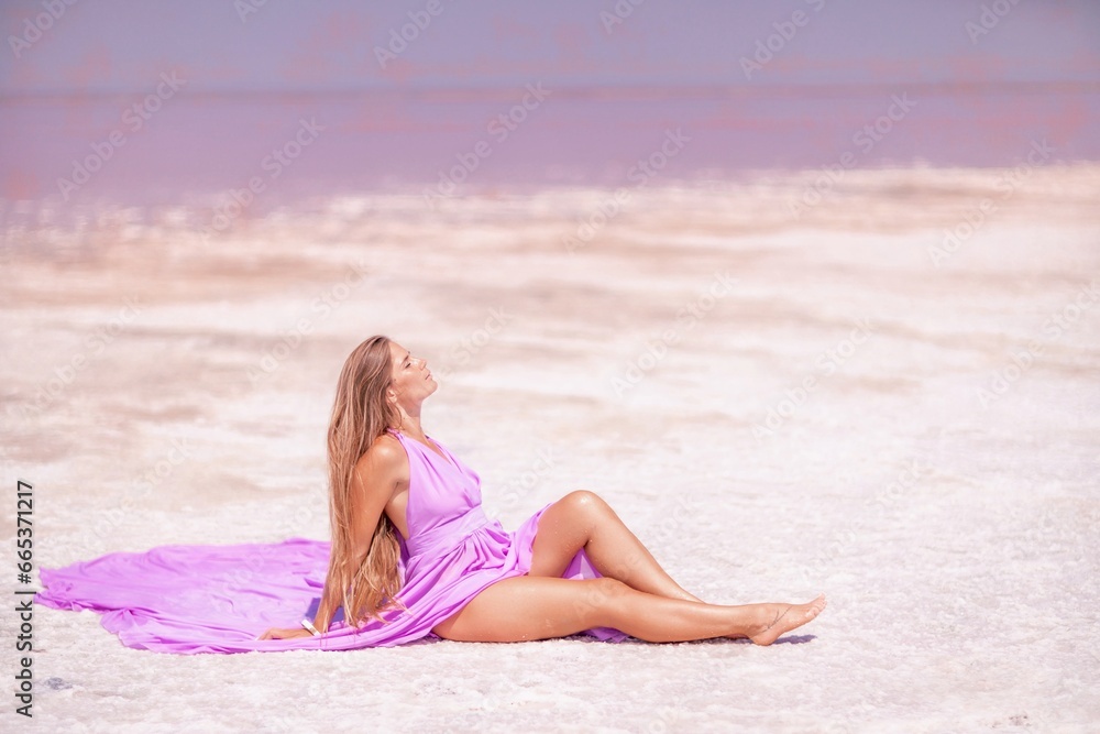 A woman in a pink dress sits on the salty shore of a pink lake and poses for a souvenir photo, creating lasting memories. A woman in a pink dress sits on the salty shore of a pink lake and poses for a souvenir photo, creating lasting memories.