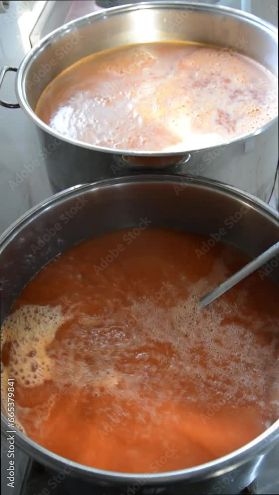 Cooking bubbles and steam with noodles added to boiling tomato and pepper soup in a pot in the kitchen Cooking bubbles and steam with noodles added to boiling tomato and pepper soup in a pot in the kitchen