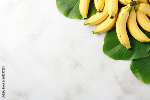 Photo of bunches of bananas lying on the leaves of a banana tree. Tropical background. White minimalistic background. Texture of light marble. Fresh, appetizing, tasty and healthy fruit. photo