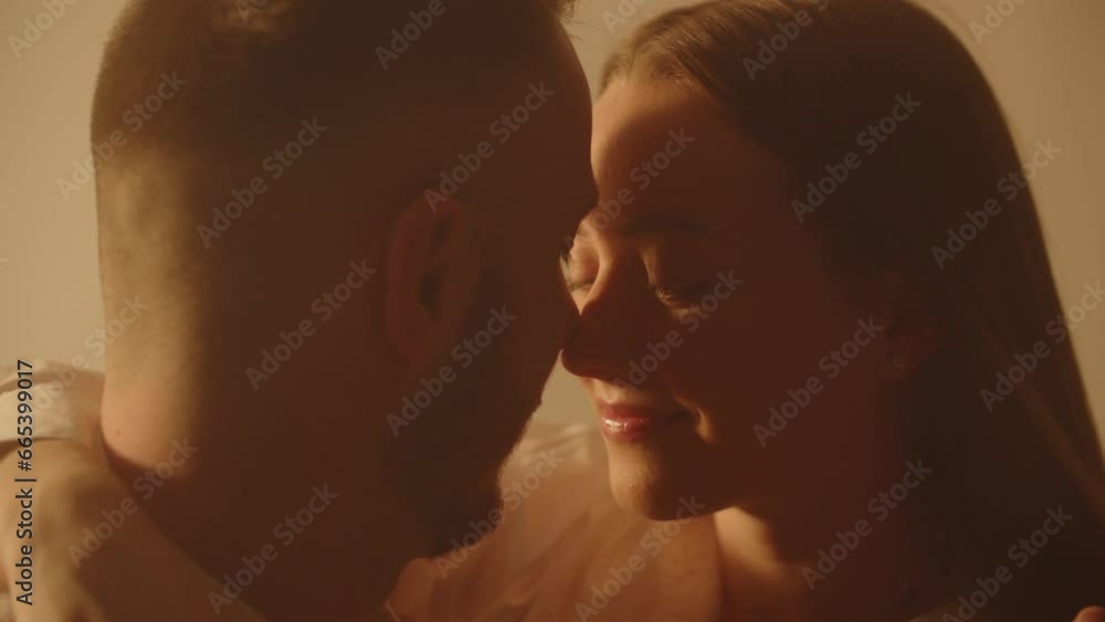 Young cheerful couple in love touch noses in bedroom. Two lovers bonding. Male touching his girlfriend nose while spending honeymoon together. Happy cute pair enjoying an intimate moment Young cheerful couple in love touch noses in bedroom. Two lovers bonding. Male touching his girlfriend nose while spending honeymoon together. Happy cute pair enjoying an intimate moment