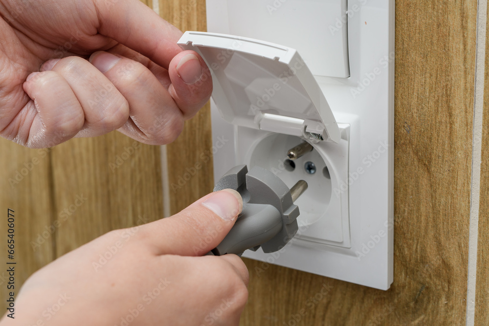 Obraz premium Wkładać wtyczkę do gniazda elektrycznego z klapką