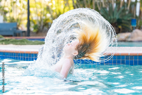 Boy swishing hair in resort swimming pool on holiday photo