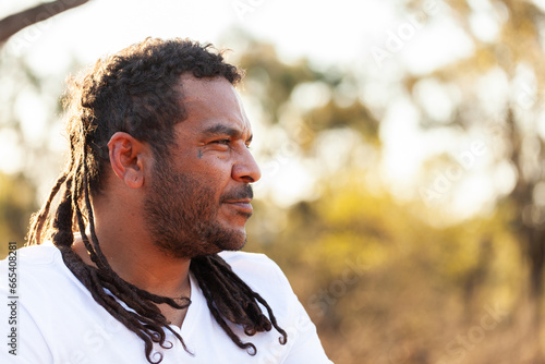 Side profile of Aboriginal Australian man looking off into bushland photo