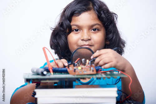 Student girl using magnifying glass working on a computer motherboard in a electronic school laboratory 