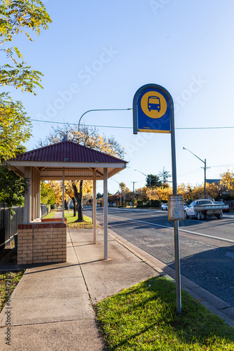 Bus stop sign and shelter on street of rural country town - public transport