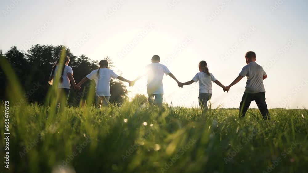 happy family.children holding hand walk run in park on green grass in summer.team of kid holding hand run with ball in nature.Kid play together as team in summer.Group of children in park in nature