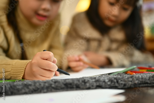 Two little girls making greeting card for New Year and Christmas while lying on floor at home