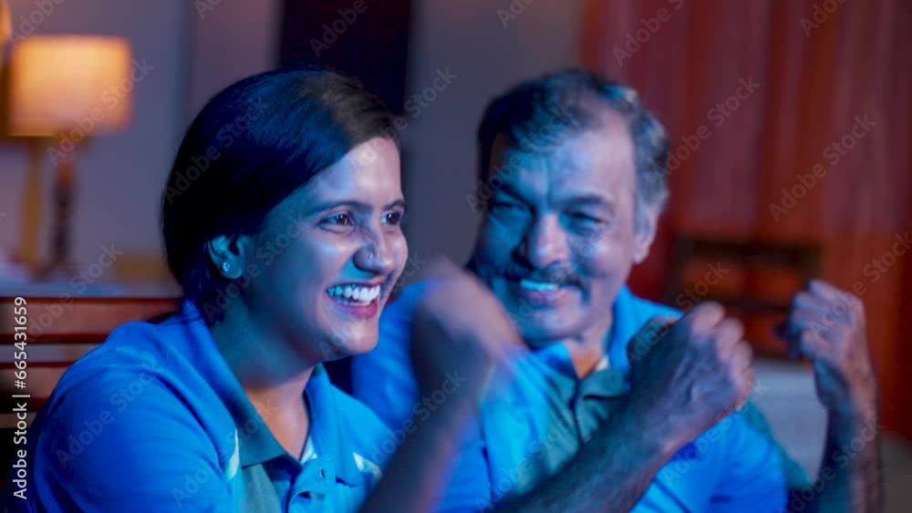 Side view of excited Indian father and Daughter shouting as India while watching cricket on tv or television at home - concept of joyful celebration, world cup match and audience