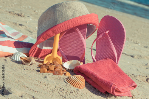 Different accessories for relax on sand at beach. Straw hat, slippes, towel. Summer time